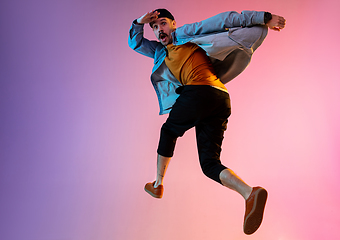 Image showing Full length portrait of happy jumping man in neon light and gradient background