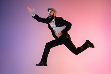 Image showing Full length portrait of happy jumping man in neon light and gradient background