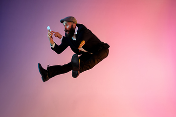 Image showing Full length portrait of happy jumping man in neon light and gradient background