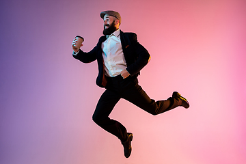 Image showing Full length portrait of happy jumping man in neon light and gradient background