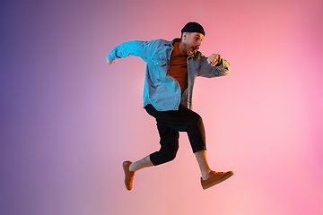 Image showing Full length portrait of happy jumping man in neon light and gradient background