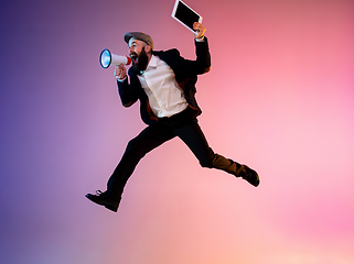 Image showing Full length portrait of happy jumping man in neon light and gradient background