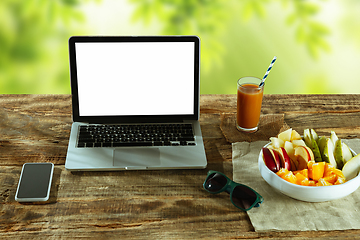 Image showing Blank laptop on a wooden table outdoors, mock up