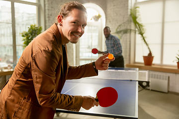 Image showing Young men playing table tennis in workplace, having fun