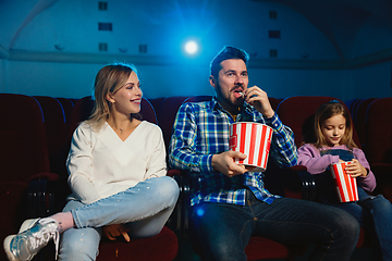 Image showing Young caucasian family watching a film at a movie theater