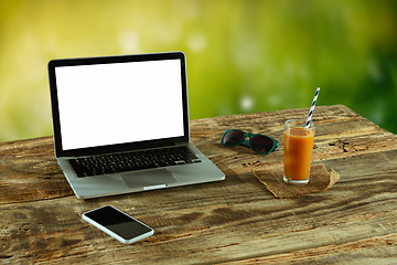 Image showing Blank laptop on a wooden table outdoors, mock up