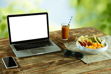 Image showing Blank laptop on a wooden table outdoors, mock up