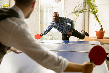 Image showing Young men playing table tennis in workplace, having fun