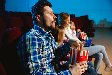 Image showing Young caucasian family watching a film at a movie theater