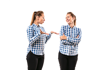 Image showing Young handsome woman arguing with herself on white studio background.