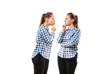 Image showing Young handsome woman arguing with herself on white studio background.