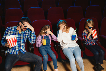 Image showing Young caucasian family watching a film at a movie theater