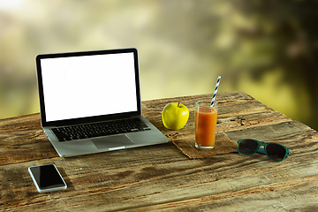 Image showing Blank laptop on a wooden table outdoors, mock up