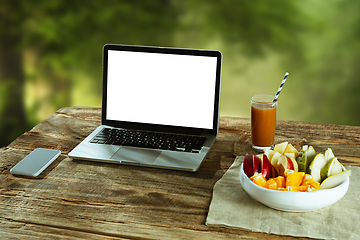 Image showing Blank laptop on a wooden table outdoors, mock up