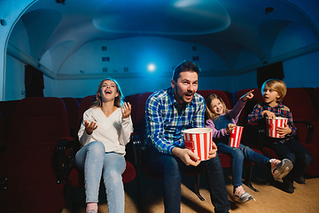 Image showing Young caucasian family watching a film at a movie theater