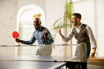Image showing Young men playing table tennis in workplace, having fun