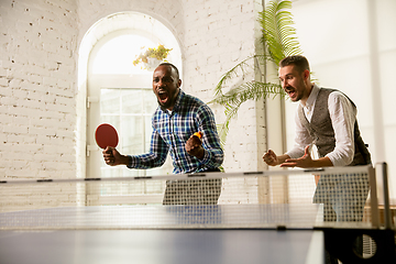 Image showing Young men playing table tennis in workplace, having fun