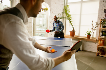 Image showing Young men playing table tennis in workplace, having fun