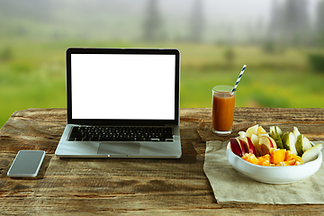 Image showing Blank laptop on a wooden table outdoors, mock up