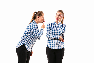 Image showing Young handsome woman arguing with herself on white studio background.