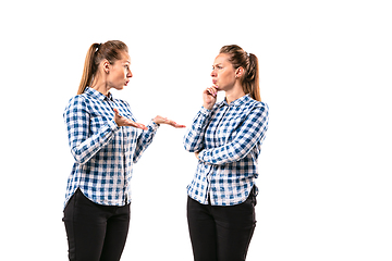 Image showing Young handsome woman arguing with herself on white studio background.