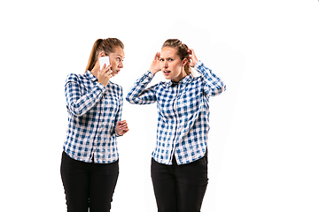 Image showing Young handsome woman arguing with herself on white studio background.