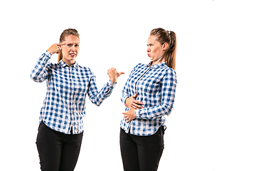 Image showing Young handsome woman arguing with herself on white studio background.