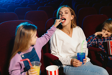 Image showing Young caucasian family watching a film at a movie theater