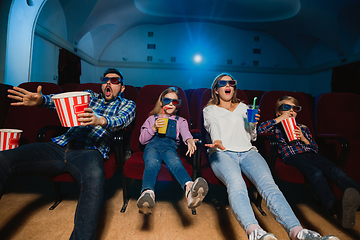 Image showing Young caucasian family watching a film at a movie theater