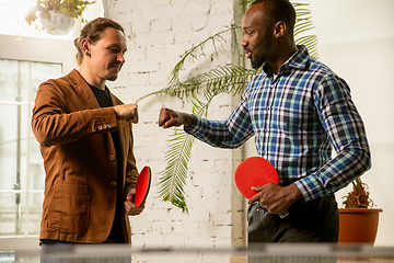 Image showing Young men playing table tennis in workplace, having fun