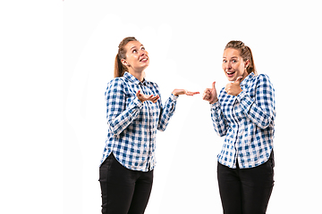 Image showing Young handsome woman arguing with herself on white studio background.