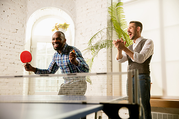 Image showing Young men playing table tennis in workplace, having fun