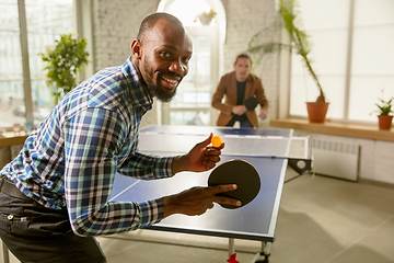 Image showing Young men playing table tennis in workplace, having fun