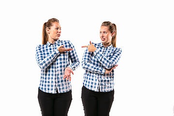 Image showing Young handsome woman arguing with herself on white studio background.