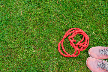 Image showing Skipping rope and sneakers on the green grass background