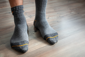 Image showing male feet in grey socks on a wooden floor