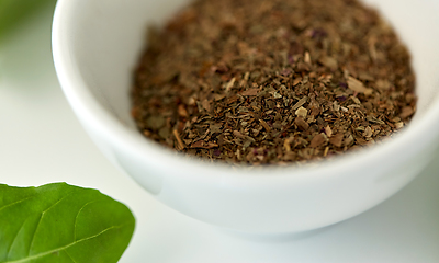 Image showing close up of dry basil seasoning in white cup