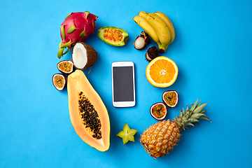 Image showing exotic fruits around smartphone on blue background