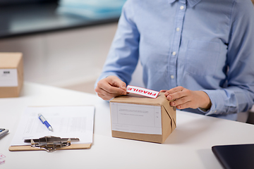 Image showing woman sticking fragile mark to parcel box