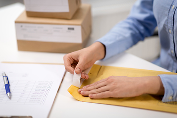 Image showing woman removing sticker from envelope with parcel