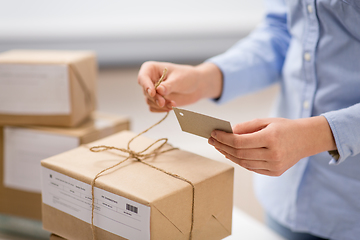 Image showing woman packing parcel and tying tag at post office