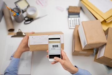 Image showing hands with smartphone scans barcode on parcel box