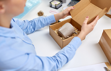 Image showing woman packing mug to parcel box at post office