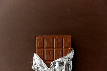 Image showing chocolate bar in foil wrapper on brown background