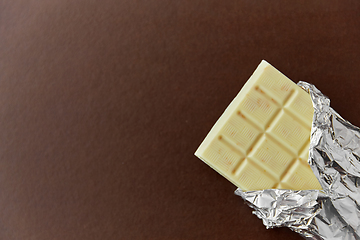 Image showing white chocolate bar in foil wrapper on brown