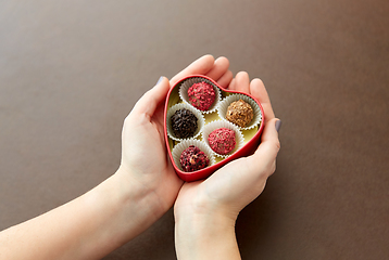 Image showing hands with candies in heart shaped chocolate box