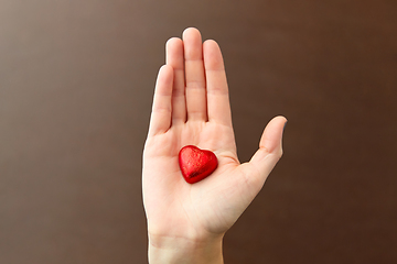 Image showing hand with red heart shaped chocolate candy