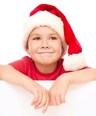 Image showing Little girl in santa hat is holding blank board