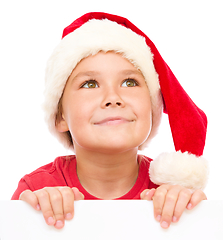 Image showing Little girl in santa hat is holding blank board