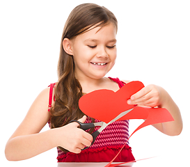 Image showing Portrait of a little girl cutting out red heart